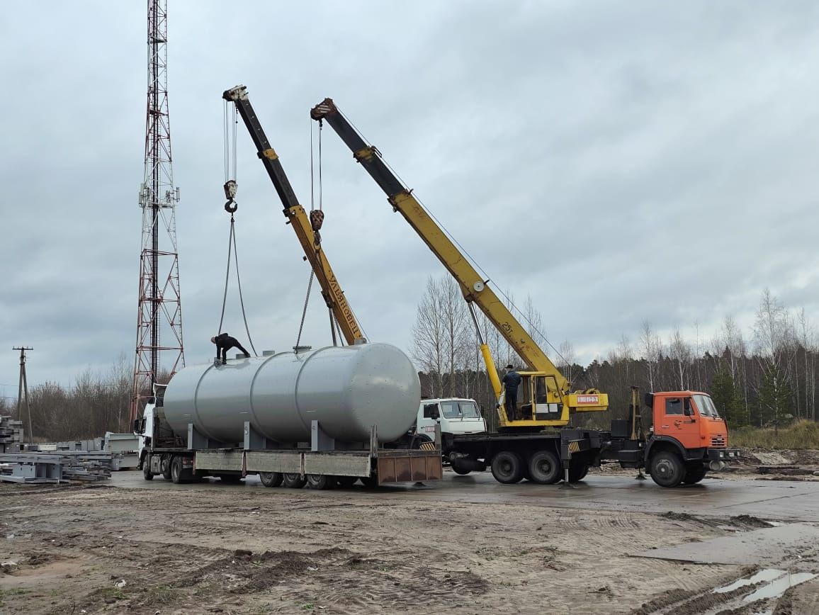 Разгрузка горизонтального бака деаэраторной установки с трала двумя автокранами на строительной площадке
